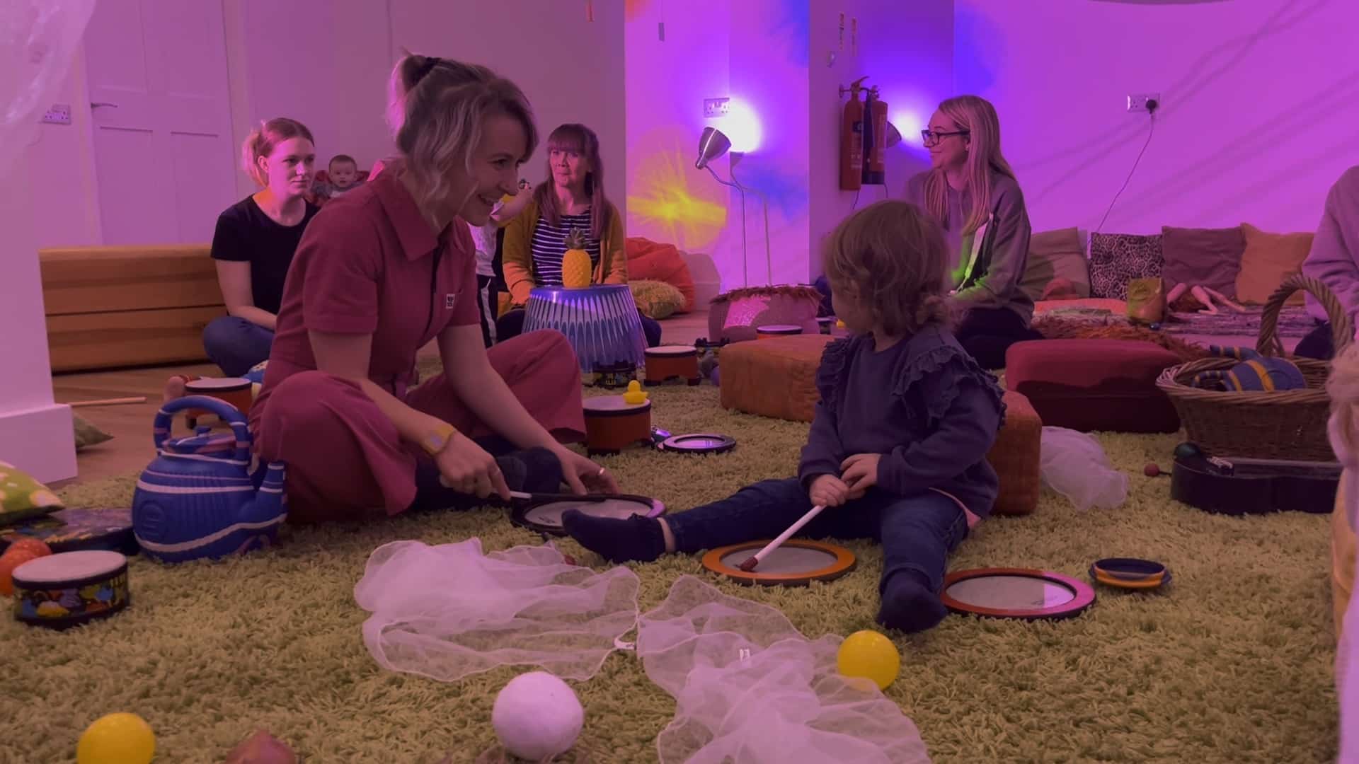 Adult and child playing on floor with balls and other objects