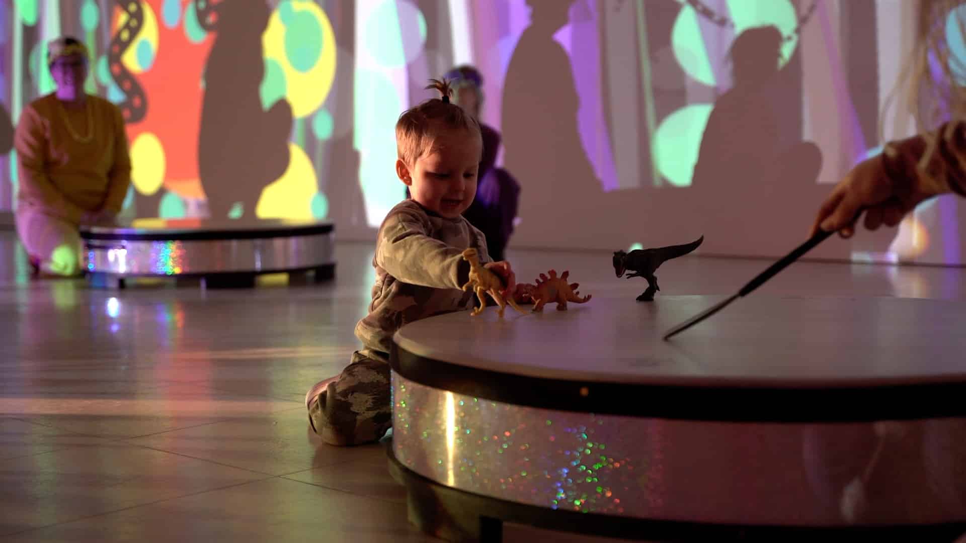 Child playing with a drum and a dinosaur